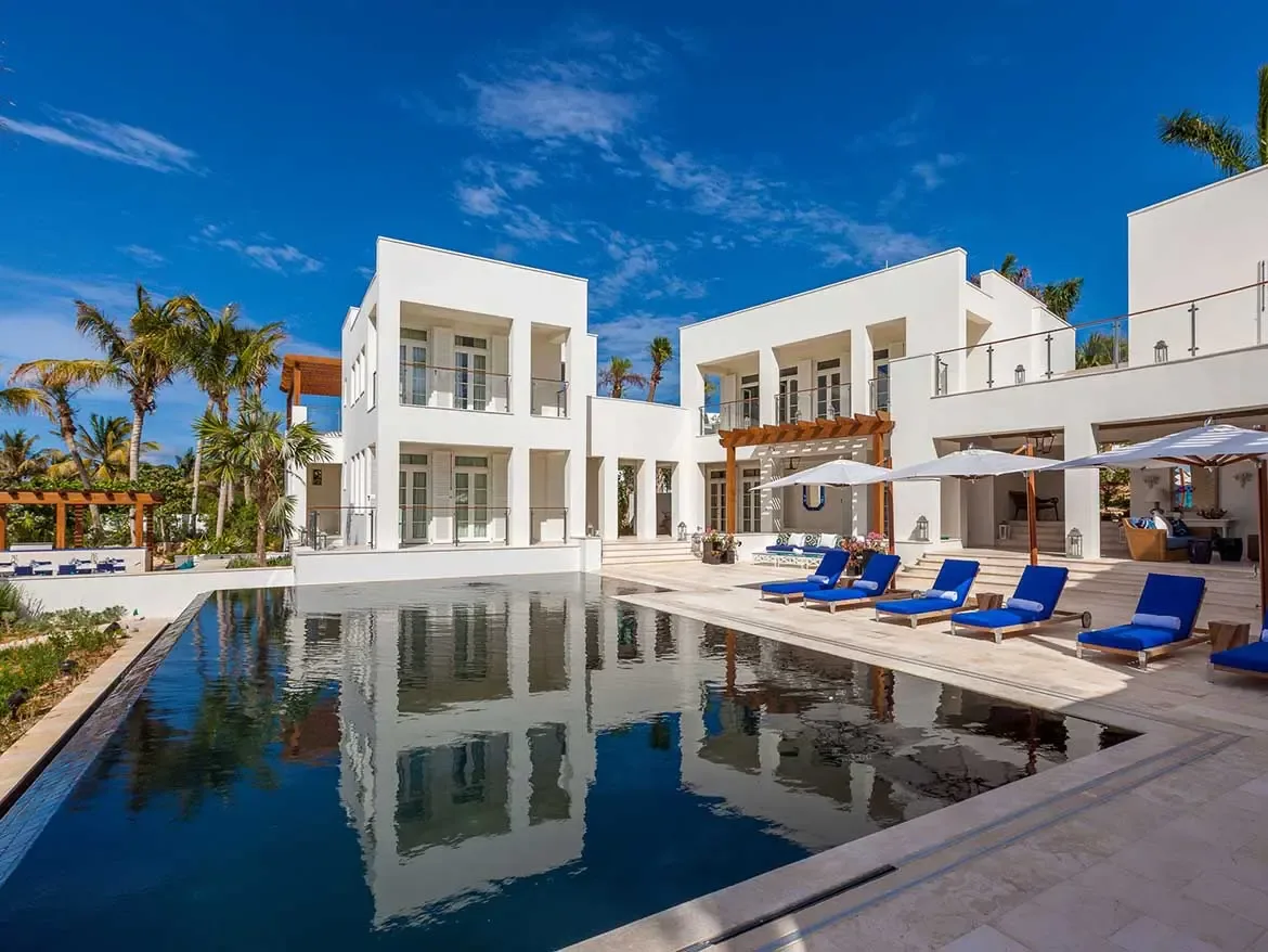Experience ultimate Caribbean luxury at the stunning Cerulean Villa in Anguilla, featuring modern white architecture and a sprawling private pool that perfectly reflects the estate's design. This world-class rental offers expansive outdoor living spaces with premium blue loungers and shaded terraces, providing an idyllic setting for a high-end island getaway.