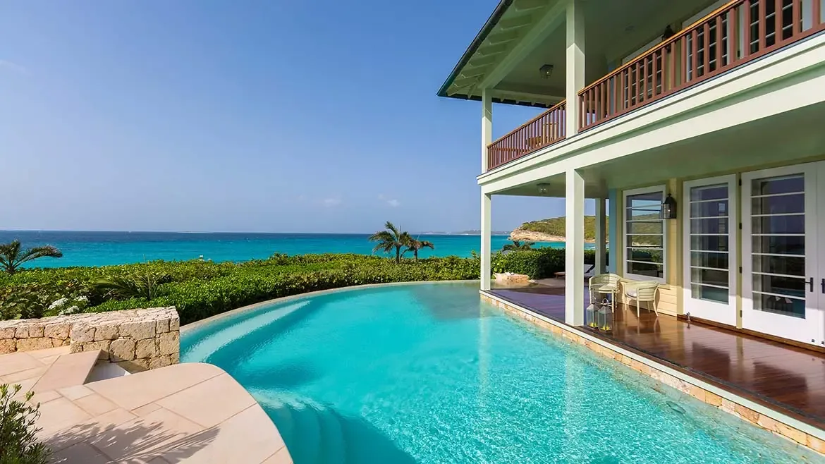 Experience the enchanting evening glow of Villa Santosha, where sophisticated architectural design meets the tranquil beauty of Long Bay, Anguilla. This stunning nighttime perspective highlights the grand estate's warm, inviting ambiance, perfectly set against the deep blue of a Caribbean twilight.