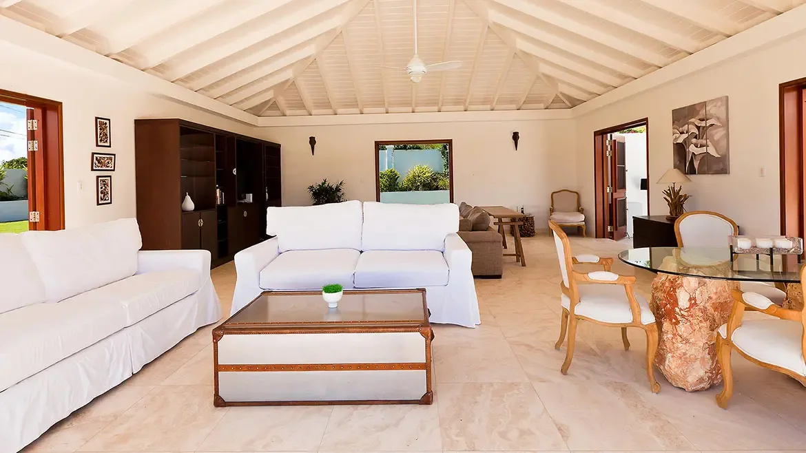 This bright open-plan living and dining room at Le Bleu Villa features vaulted wood ceilings, crisp white seating, and an airy coastal design. The space captures the comfort and sophistication expected from a luxury Anguilla villa.