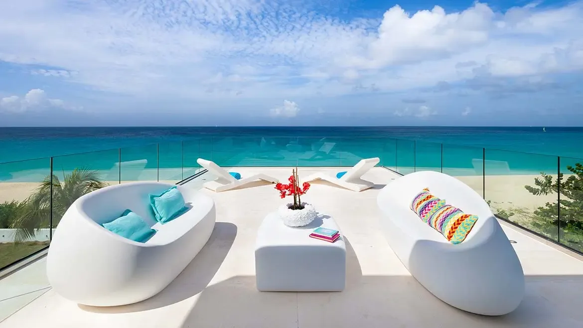 Relax in style on the modern terrace of this luxury Anguilla beach house, offering stunning panoramic views of the turquoise Caribbean Sea. This elegant outdoor lounge area features designer sculptural furniture and glass railings for an unobstructed oceanfront experience.