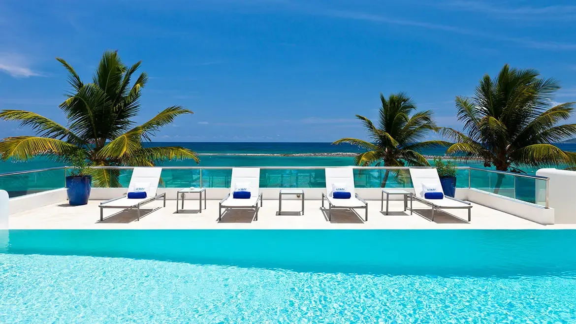 Le Bleu Villa's ocean-facing infinity pool and sun deck offer a clean, contemporary setting for relaxed Caribbean living. Framed by palms and bright blue water, this image highlights one of the villa's signature outdoor amenities.