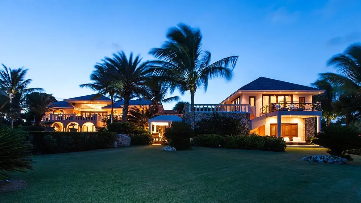 Experience the pinnacle of Caribbean luxury at Villa Indigo, a stunning estate in Anguilla featuring elegant stone architecture and lush tropical gardens. This expansive vacation rental offers a secluded island retreat with warm, inviting interiors and sprawling outdoor living spaces perfect for evening relaxation under the palm trees.