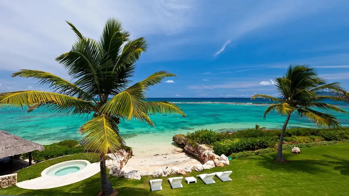 Set above vivid turquoise water, Le Bleu Villa enjoys a serene beachfront perspective framed by palms and tropical landscaping. This exterior angle reinforces the exclusivity and natural beauty of the Anguilla setting.