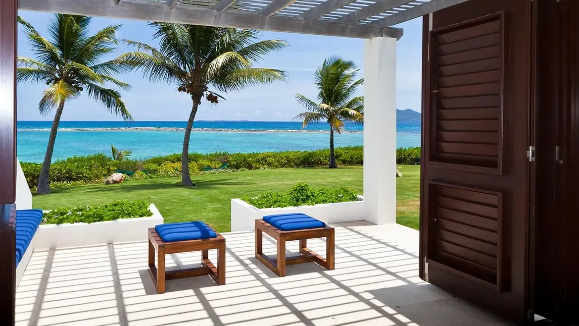 A covered patio with stylish bar seating looks out toward the turquoise Caribbean, creating a relaxed yet elevated entertaining space. This image presents Le Bleu Villa as an ideal home for refined indoor-outdoor island living.