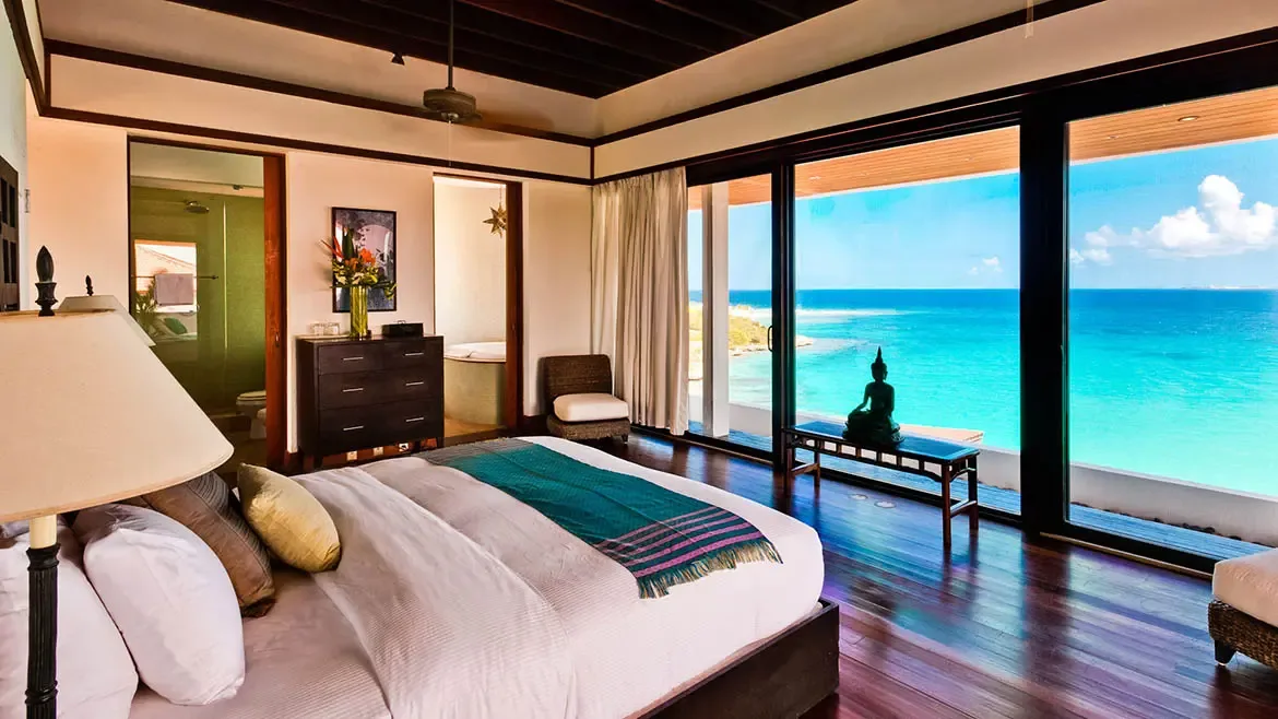 The elegant dining room at Zenaida Estate accommodates 12 guests in refined comfort, with floor-to-ceiling windows framing the stunning Caribbean views.