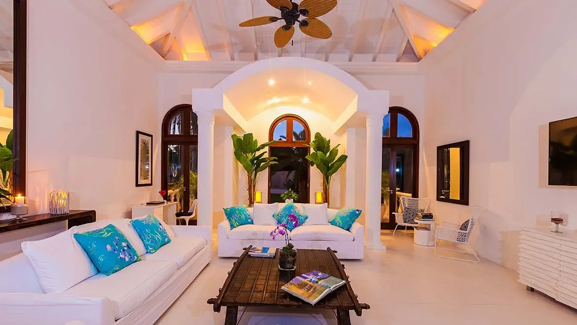 Experience the ultimate Caribbean escape in the elegantly appointed living area of Villa Indigo in Anguilla. This bright, open-plan space features vaulted ceilings, arched architecture, and vibrant turquoise accents, perfect for relaxing in true island style.