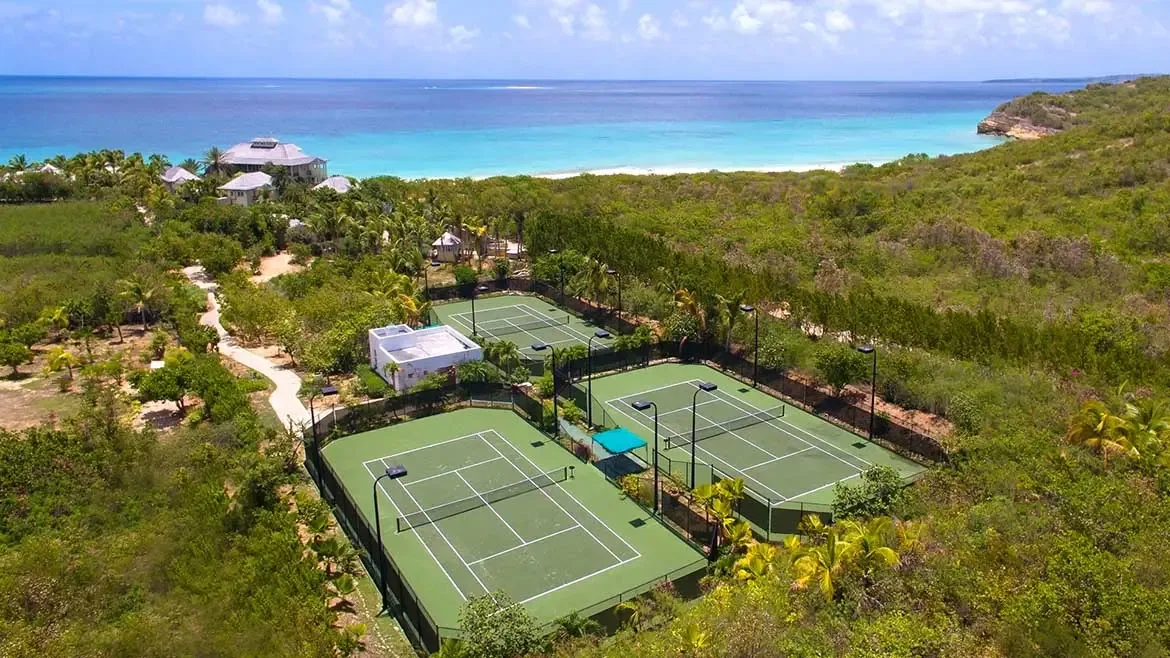 Bask in the natural light of Villa Santosha's expansive living area, where floor-to-ceiling glass doors frame breathtaking views of the turquoise Caribbean Sea along Long Bay.