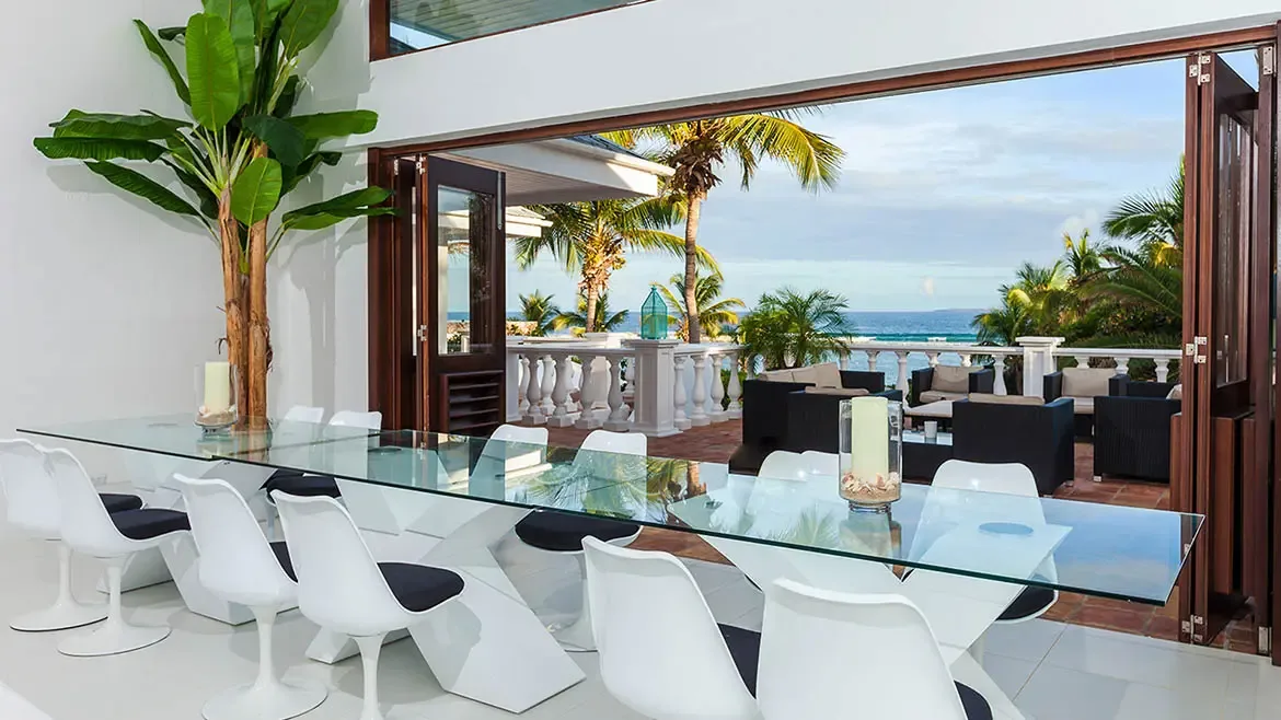 Experience seamless indoor-outdoor living at Villa Indigo, featuring a sophisticated glass-top dining area that opens onto a sprawling oceanfront terrace. This luxury Anguilla villa rental offers breathtaking Caribbean views and elegant modern design, perfect for hosting unforgettable sunset dinners.