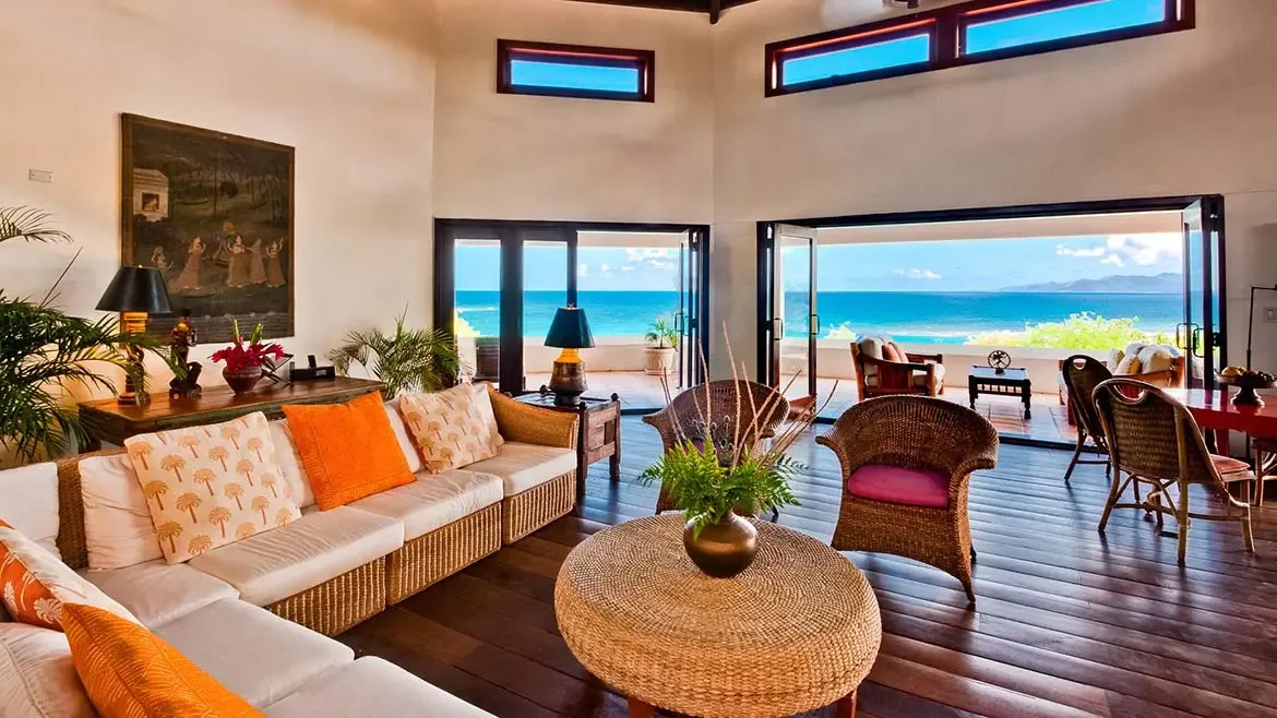 Experience the ultimate in Caribbean indoor-outdoor living from the highest elevation of Zenaida Estate, where this expansive living room offers sweeping views across three acres of lush gardens to the turquoise sea and St. Martin beyond.