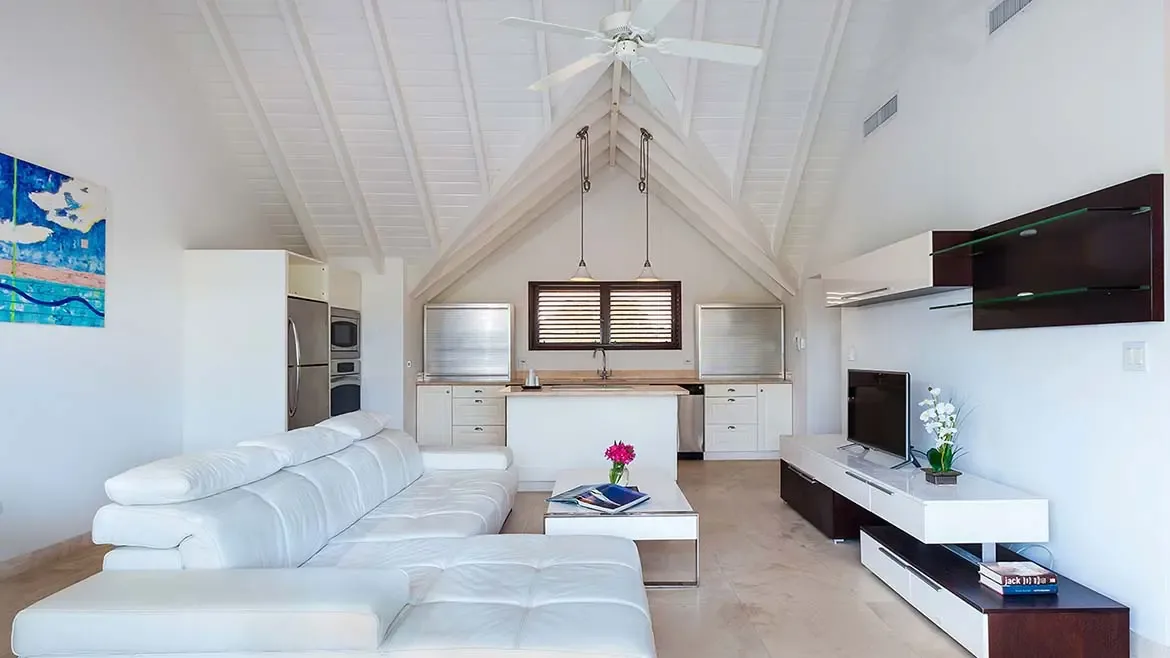 This ultra-modern living area at Villa Indigo features soaring vaulted ceilings and a clean white aesthetic perfect for a luxury Anguilla vacation. The open-concept layout seamlessly connects the designer lounge space to a sleek, fully-equipped gourmet kitchen.