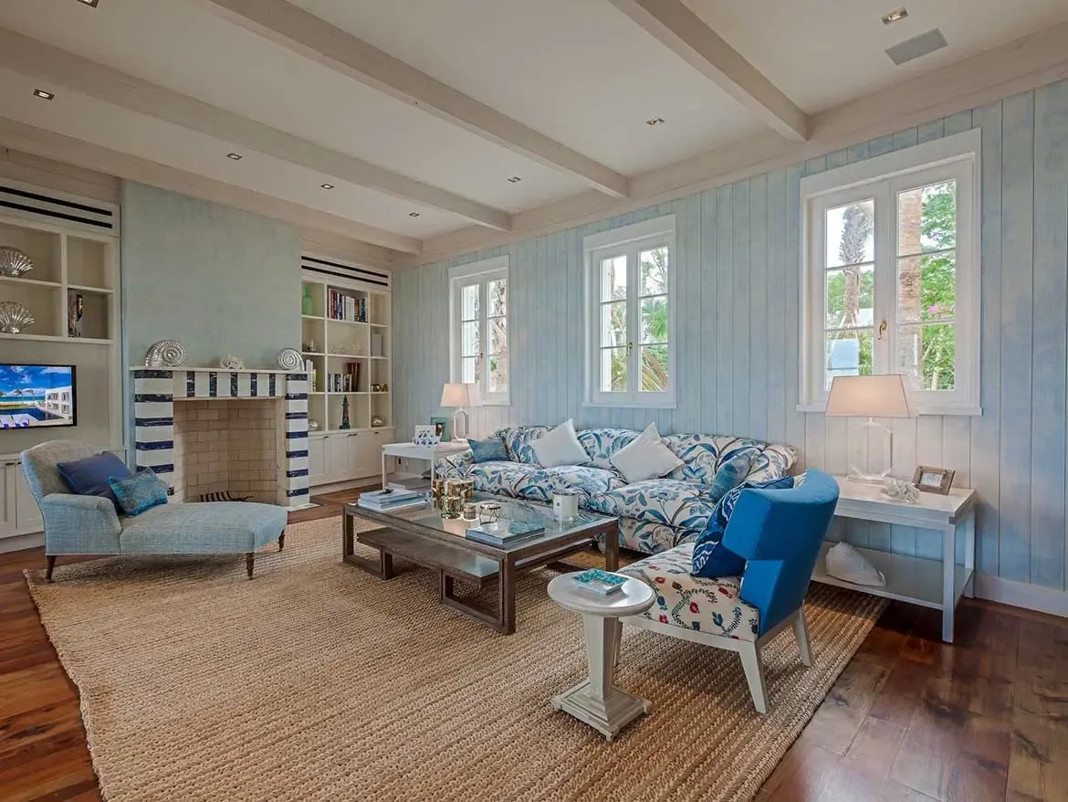 This expansive living area at Villa Cerulean features a coastal-inspired design with plush floral seating and elegant blue accents. Bathed in natural light from large windows, the space offers a sophisticated yet comfortable atmosphere for relaxing after a day in the Anguilla sun.