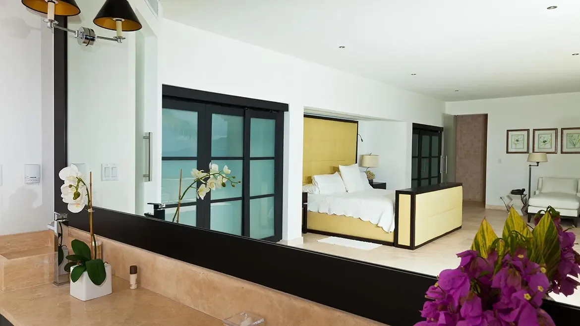 Viewed from the bathroom, this master suite reveals layered design details including a plush upholstered bed, marble vanity, and sliding glass panels. The composition underscores the spacious, upscale finish of Le Bleu Villa's interiors.