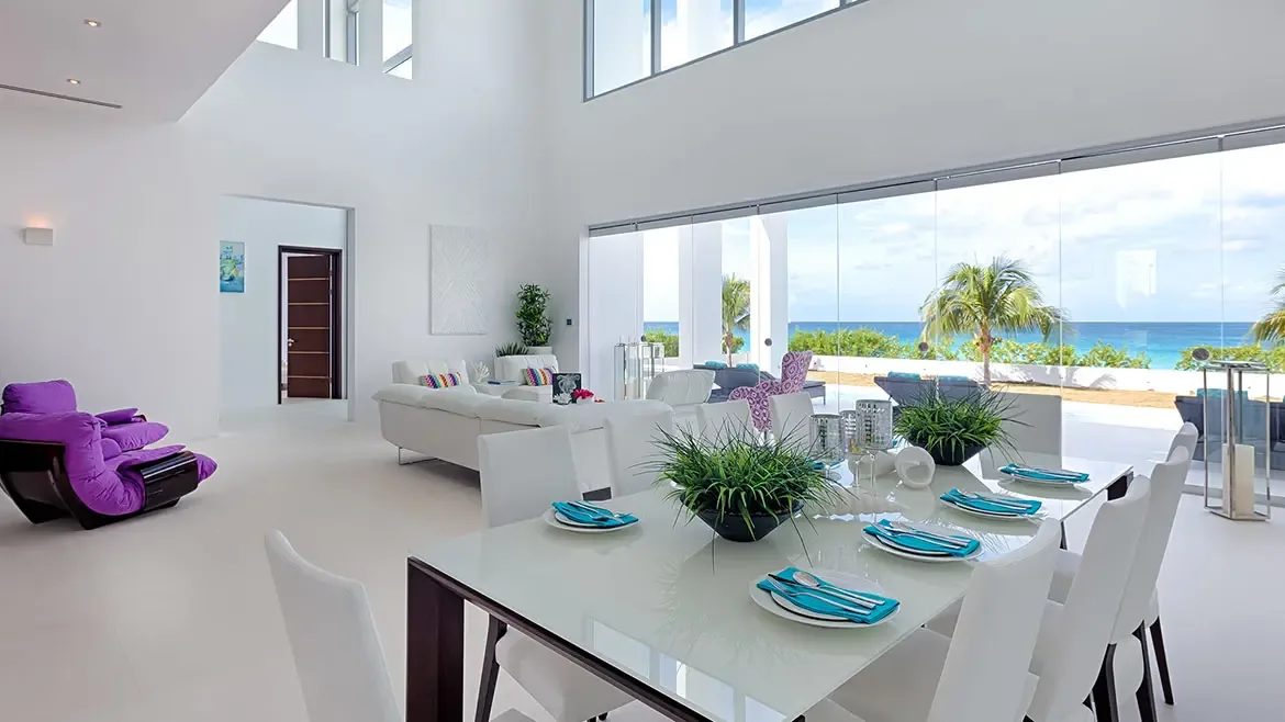Experience ultimate Caribbean elegance in this bright, open-plan dining and living area featuring panoramic floor-to-ceiling views of the turquoise sea. This modern luxury villa in Anguilla offers seamless indoor-outdoor living with high-end furnishings and a sophisticated minimalist aesthetic.