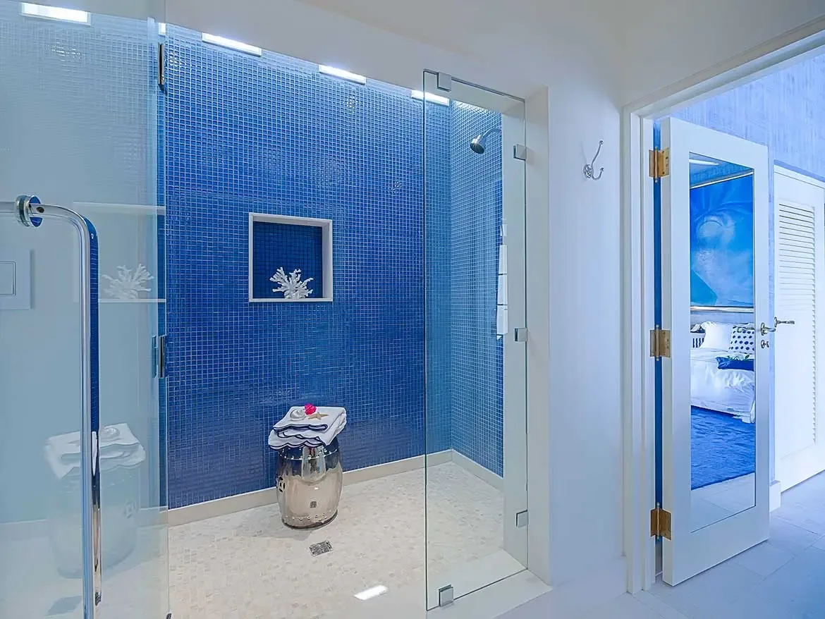 This stunning master bathroom at Cerulean Villa features a spacious walk-in shower adorned with vibrant blue mosaic tiles and elegant coastal decor. The modern design seamlessly integrates with the villa's serene atmosphere, offering a luxurious sanctuary for guests in beautiful Anguilla.