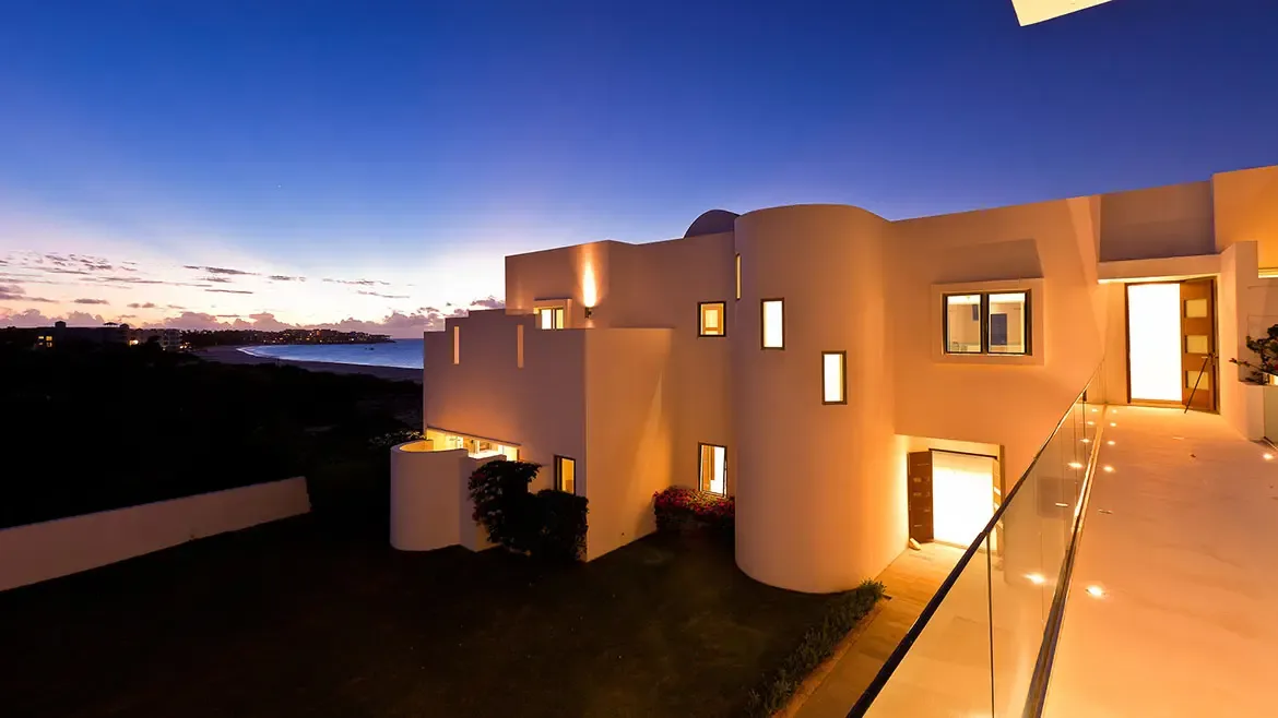Experience the epitome of Caribbean elegance at this modern luxury villa in Anguilla, featuring striking white architecture and panoramic sunset views. This stunning beachfront estate offers a sophisticated sanctuary with its sleek design, warm ambient lighting, and breathtaking vistas of the coastline.