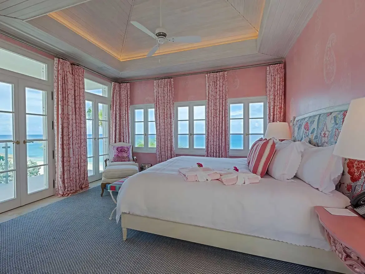 Wake up to breathtaking turquoise ocean views in this elegantly appointed pink bedroom, featuring a plush king-size bed and direct balcony access. This light-filled sanctuary combines tropical charm with modern luxury, creating the perfect retreat for your Caribbean escape at Cerulean Villa.