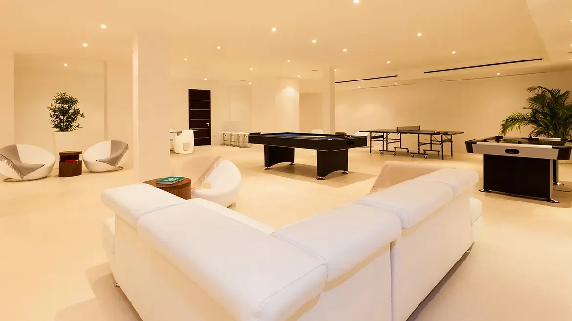 Indulge in premier indoor entertainment within the villa's expansive game room, featuring a professional pool table, ping pong, and air hockey. This sleek, modern lounge area provides the perfect retreat for guests seeking fun and relaxation in a sophisticated Anguilla beach house setting.