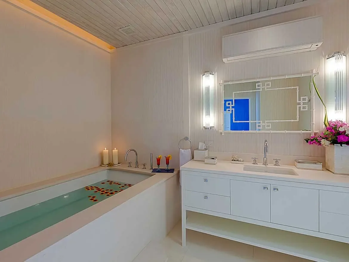 Indulge in ultimate relaxation within this spa-inspired ensuite, featuring a deep soaking tub adorned with rose petals and romantic candlelight. The sleek modern vanity and designer accents create a serene sanctuary, perfect for unwinding in style during your luxury villa getaway in Anguilla.