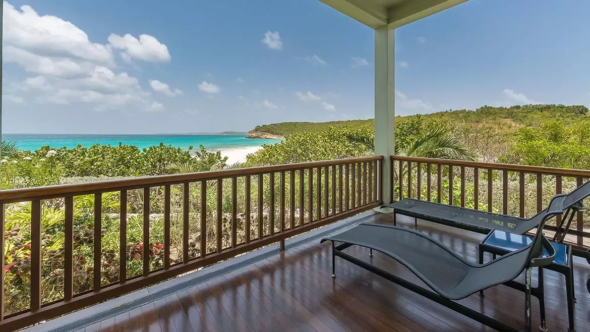 Wake up to the gentle sounds of the Caribbean in this exquisitely appointed bedroom at Villa Santosha, featuring vaulted azure ceilings and sweeping views of Long Bay, Anguilla.