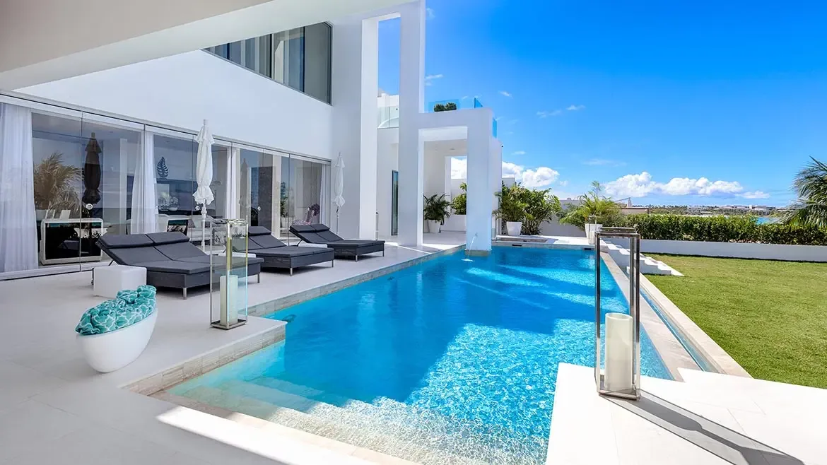 Experience ultimate relaxation at this ultra-modern Anguilla beach house featuring an expansive sparkling pool and sleek sun loungers. The minimalist white architecture provides a stunning backdrop for a private Caribbean getaway, perfect for travelers seeking high-end luxury and breathtaking island views.