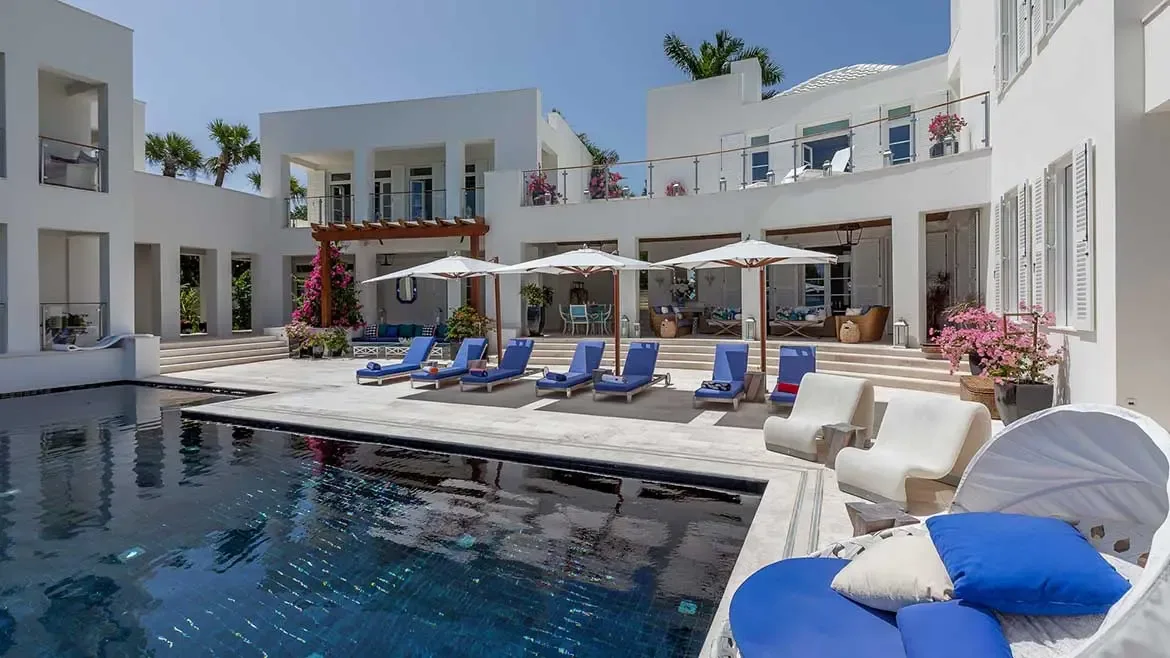 This breathtaking view of Cerulean Villa in Anguilla showcases its expansive private pool deck, featuring multiple lounge areas and pristine white Mediterranean-style architecture. The ultra-luxury estate offers a seamless indoor-outdoor living experience, perfect for high-end Caribbean vacations and exclusive retreats.