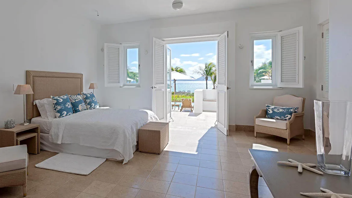 Bright white bedroom with an open-concept layout leading to a terrace with ocean views.