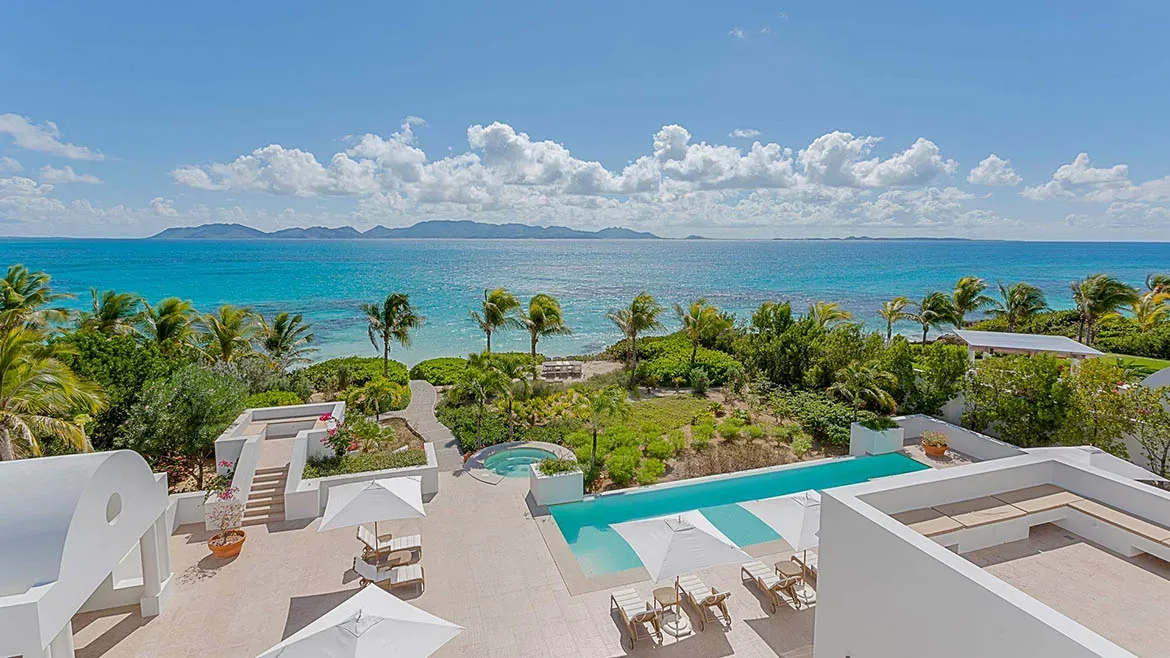 Aerial perspective of the luxury pool area overlooking the turquoise waters of Rendezvous Bay.