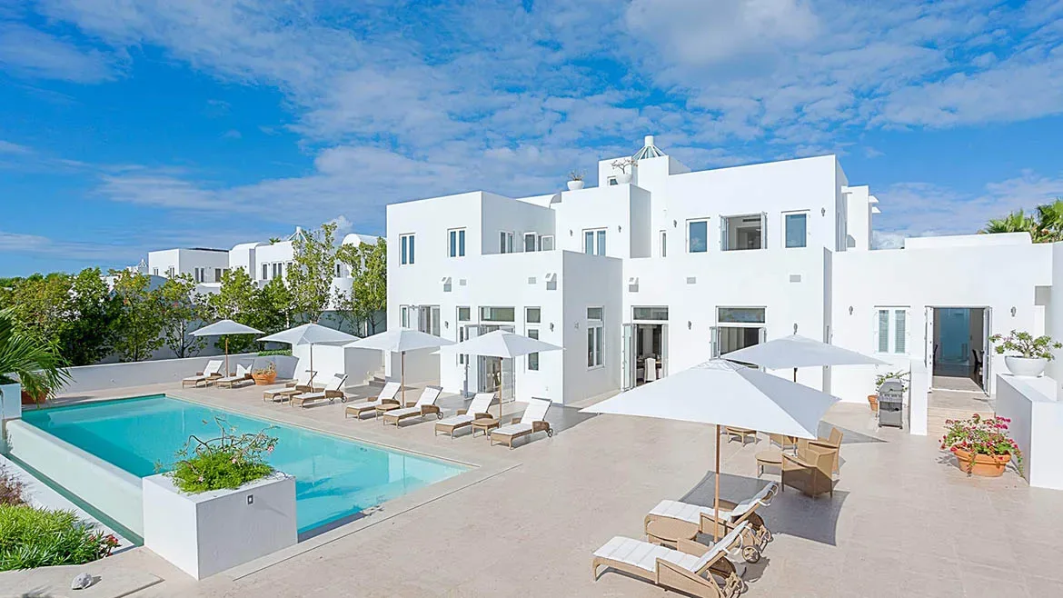 Wide shot of the white modern architecture of Villa Arushi featuring a large swimming pool and lounge area.