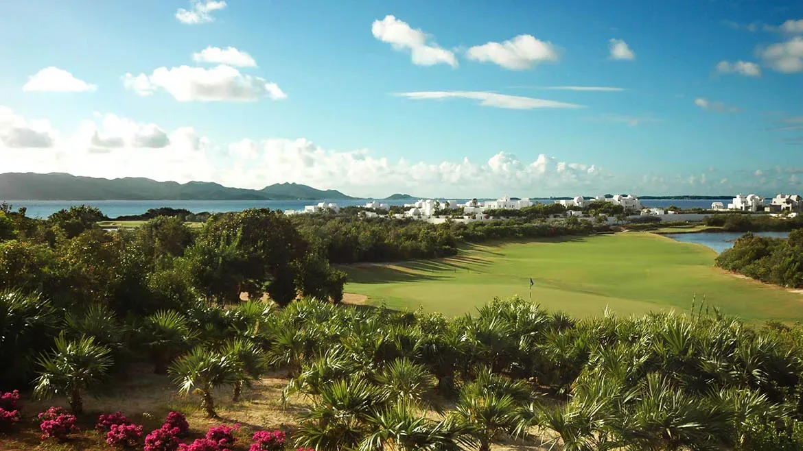 Panoramic view of a lush green golf course and turquoise ocean waters from Villa Arushi in Anguilla.