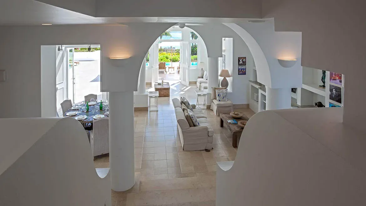High-angle view of the open-concept living area and dining room featuring elegant white architectural arches.