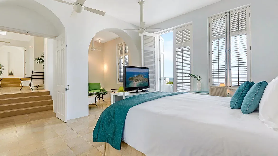 Spacious bedroom with arched doorways, teal accents, and views of the Caribbean coast.