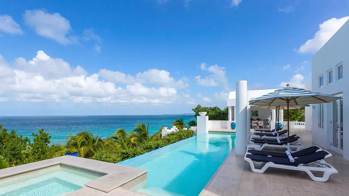 Infinity pool and sun loungers overlooking the turquoise ocean at Villa Elements.