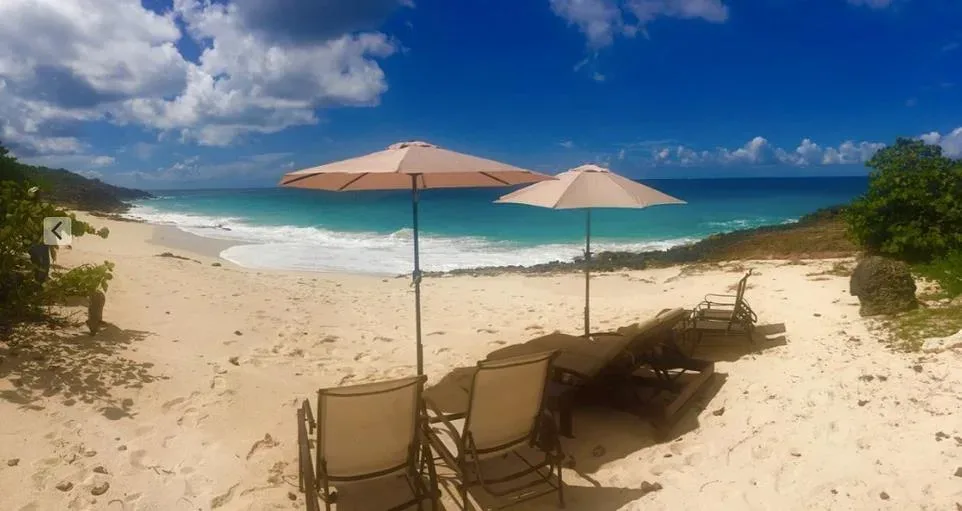 Beach lounge chairs and sun umbrellas set on the white sands of Limestone Bay.