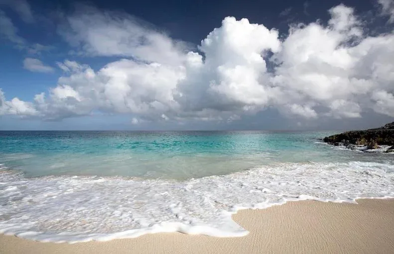 A wide view of the pristine white sand beach and turquoise waters of Limestone Bay.