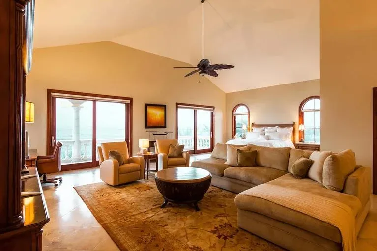 Wide interior shot of the master bedroom suite showcasing the high vaulted ceiling and lounge furniture.