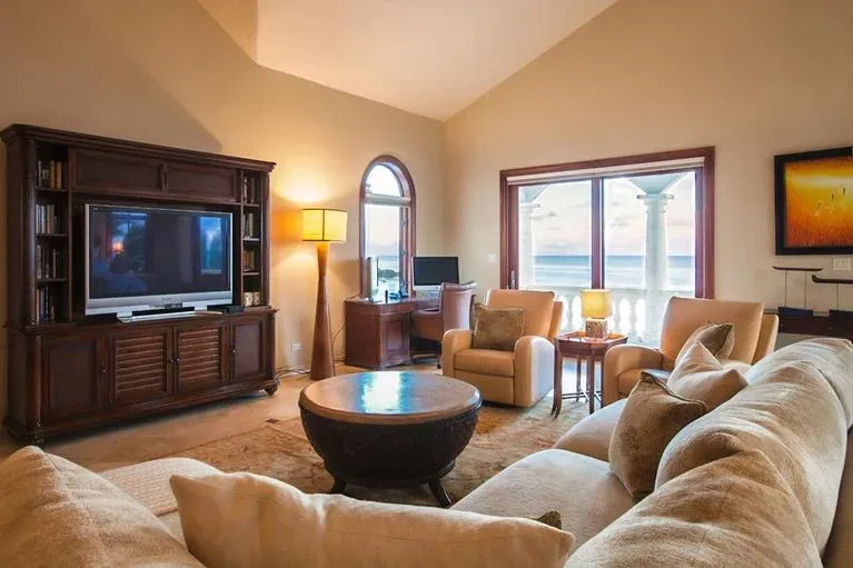 Master bedroom lounge area with a large television, comfortable seating, and neutral tones.