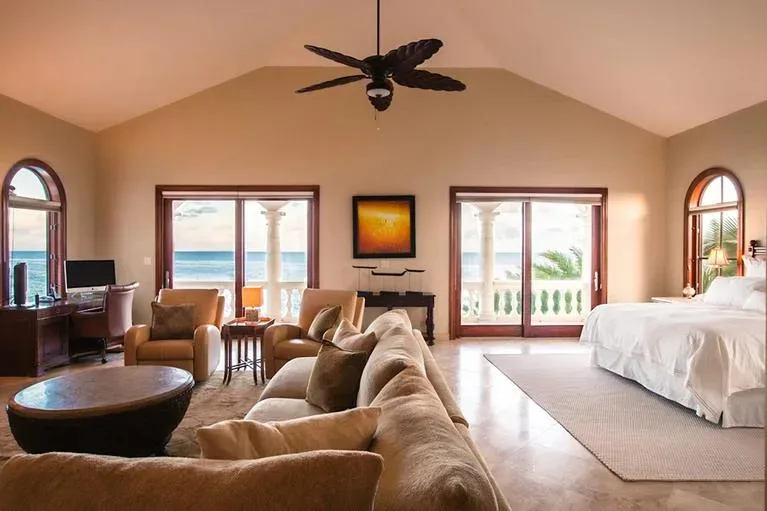 Spacious master bedroom suite featuring a sitting area with plush sofas and a view of the Caribbean Sea.