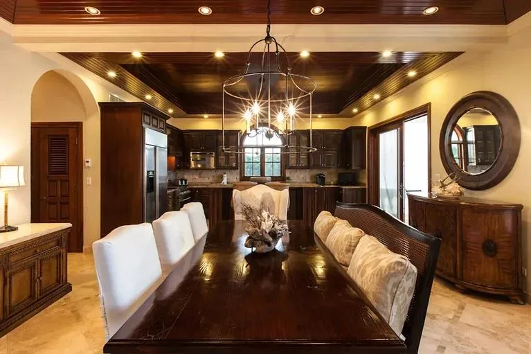 Sophisticated dining room with a long dark wood table, white upholstered chairs, and a modern metal hoop chandelier.