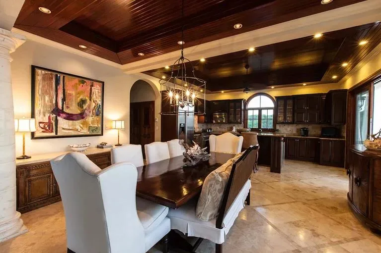 Open concept dining area and gourmet kitchen with rich dark wood cabinetry and polished stone floors.