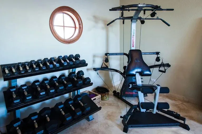 Fitness room featuring a Bowflex strength trainer and a multi-tier rack of dumbbells.