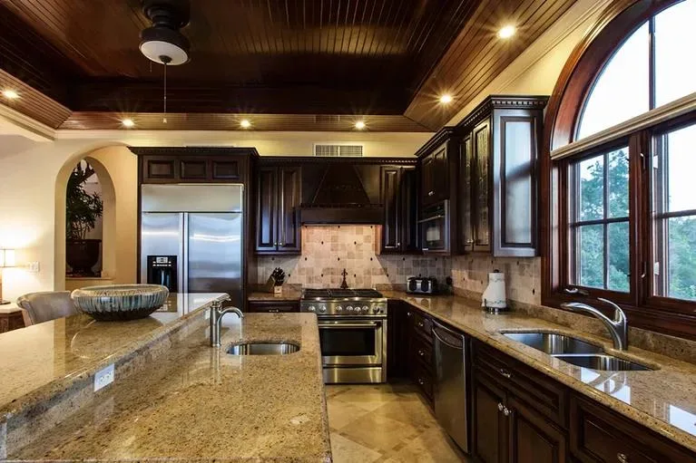 Gourmet kitchen with dark wood cabinetry, granite countertops, and professional stainless steel appliances.