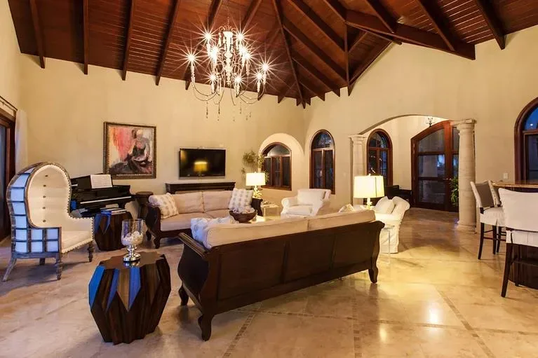 Elegant interior of the living area featuring a dark wood piano, plush sofas, and high vaulted wooden ceilings.