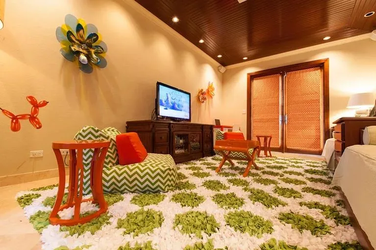 Wide view of the colorful lounge area with a cozy seating arrangement and a dark wood media console.