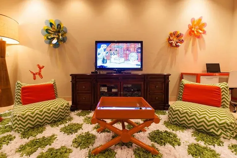 Vibrant media room with a flat-screen TV, chevron patterned bean bag chairs, and orange decorative furniture.