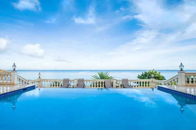 Wide view of the swimming pool and stone balustrade facing the turquoise Caribbean Sea.