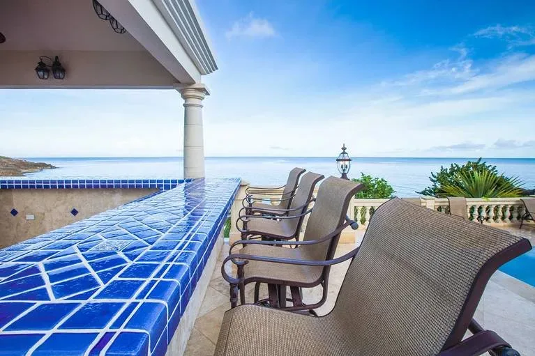 Blue tiled outdoor bar with high-back chairs overlooking the ocean at Villa Sandcastle.