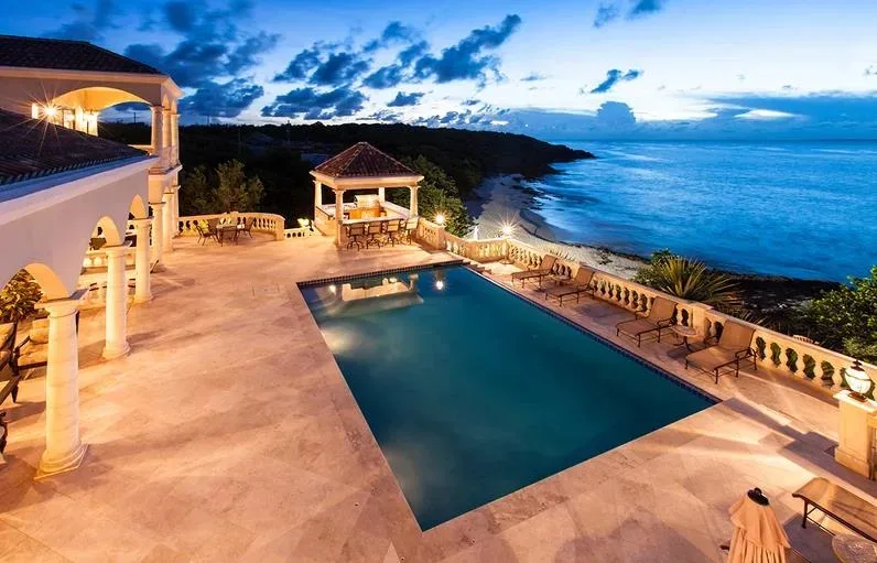 An evening wide shot of the illuminated swimming pool and poolside gazebo at Villa Sandcastle.