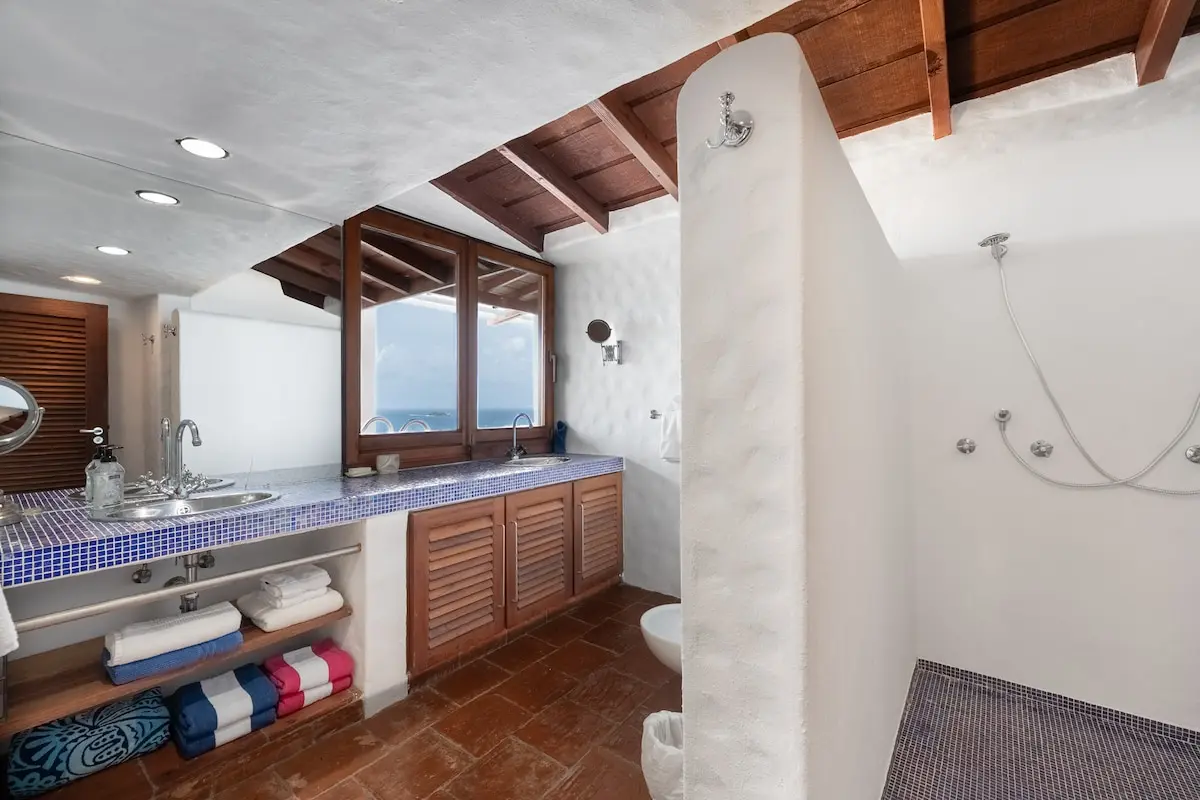 Bathroom with double vanity, open shower, and ocean outlook.