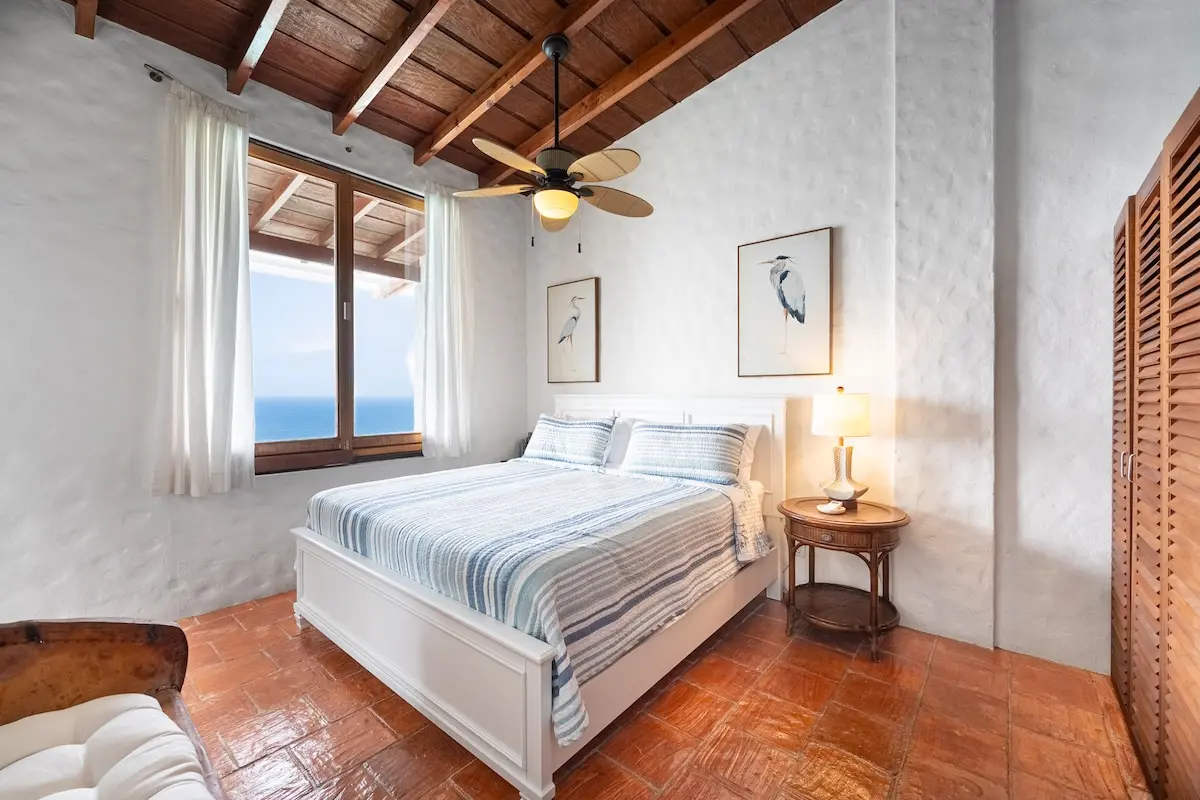 Bedroom overlooking the ocean through large windows.