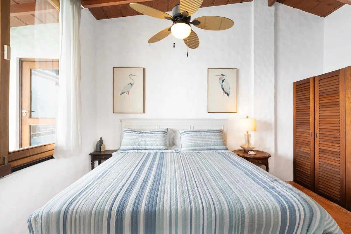 Bright guest bedroom with king bed and exposed wood ceiling.